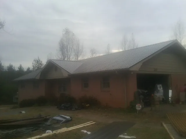 Gray metal roof on a stucco house with an attached garage in Liberty